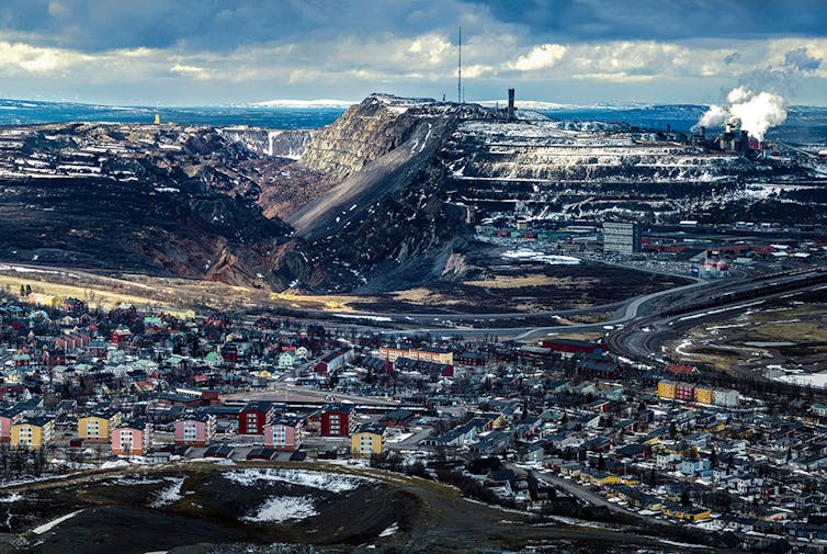 An aerial view of the Swedish town Kiruna, with an iron ore mine towering over it in the background.