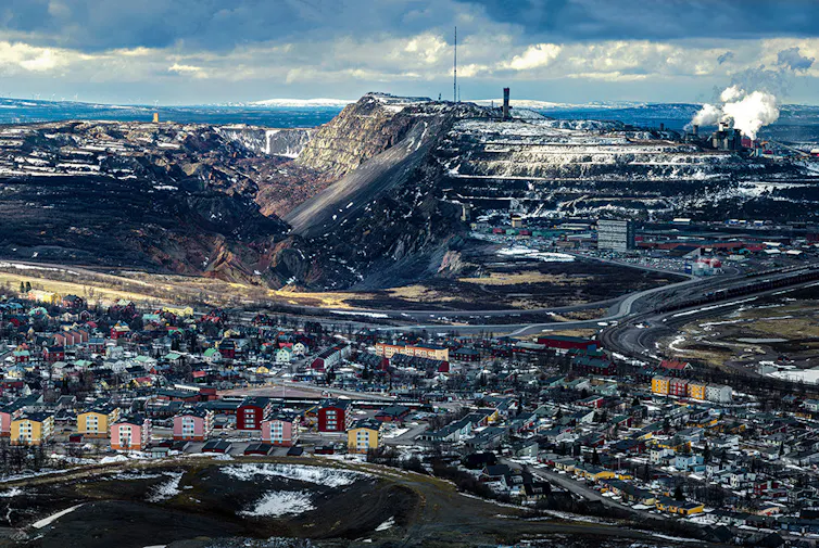 An aerial view of the Swedish town Kiruna, with an iron ore mine towering over it in the background.