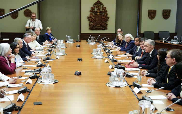 Mesa de madera de deuda con un grupo de personas, en su mayorĆa hombres, a cada lado.
