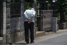 Un hombre mayor con la espalda curvada camina por un sendero.