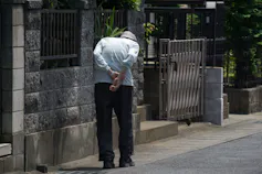 Un hombre mayor con la espalda curvada camina por un sendero.