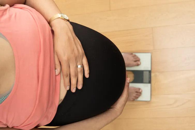 A pregnant woman standing on scales.