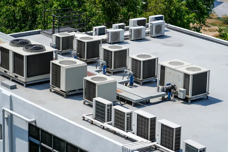 Multiple external units of air conditioning and ventilation systems installed on the roof of a large building.
