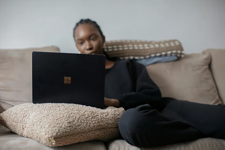 Woman sits on couch looking at laptop