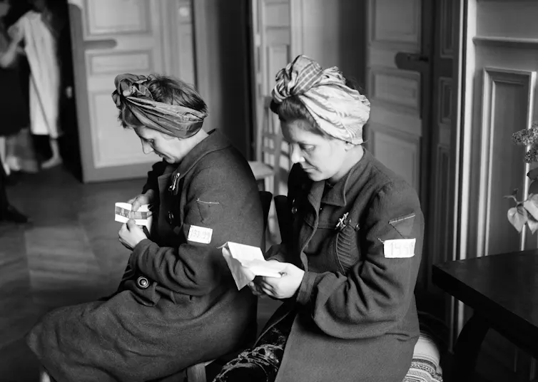 Des survivantes des camps d’extermination, lisent des documents dans un centre d’accueil pour femmes déportées en avril 1945 à Paris, à la fin de la Seconde Guerre mondiale