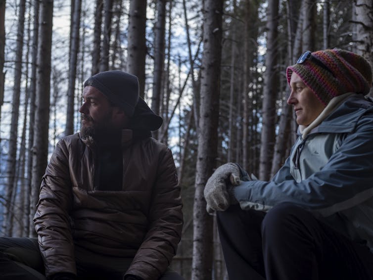 man and a woman sitting in forest