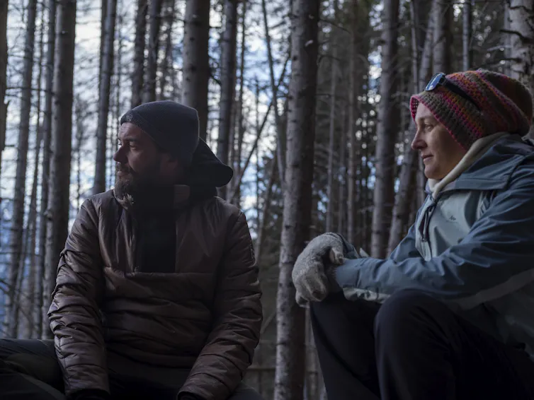 man and a woman sitting in forest