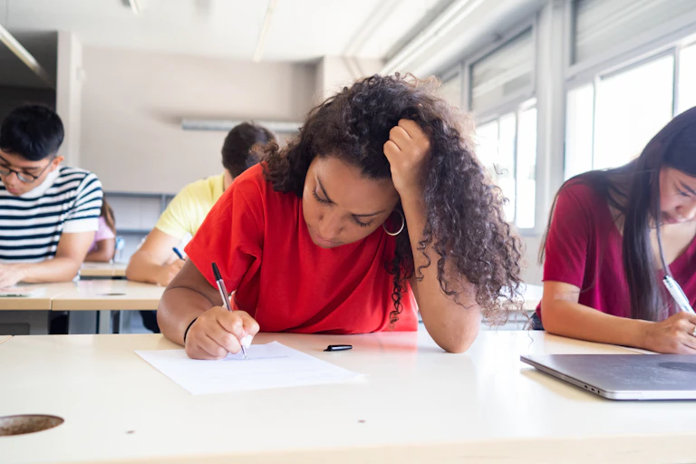 Girl frowning while doing test in classroom