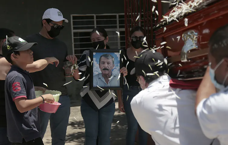 A woman holds a picture of murdered Mexican journalist Fredid Roman as his casket is carried at his funeral
