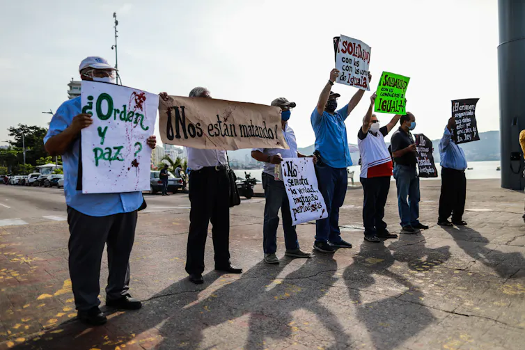 Seven journalists hold up placards in Mexico during a protest against threats to their profession.
