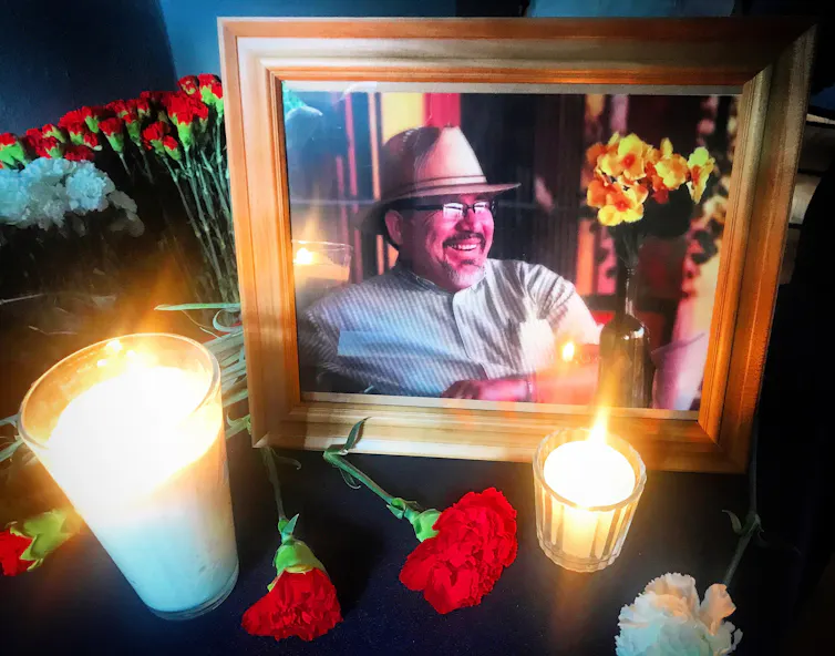 Photograph of murdered journalist Javier Valdez surrounded by candles and flowers.