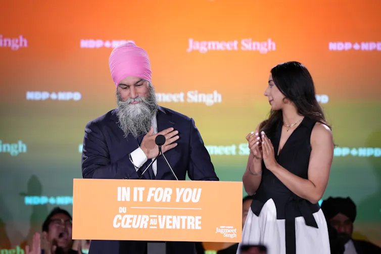 El hombre con la mano se encuentra con su corazón, la mujer se para al lado del aplaudido.