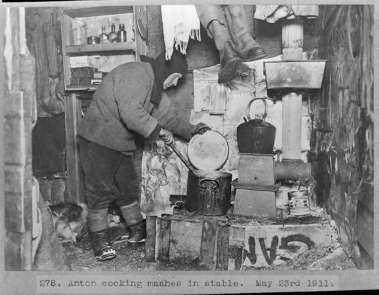 A man hunched over cooking on a makeshift stove