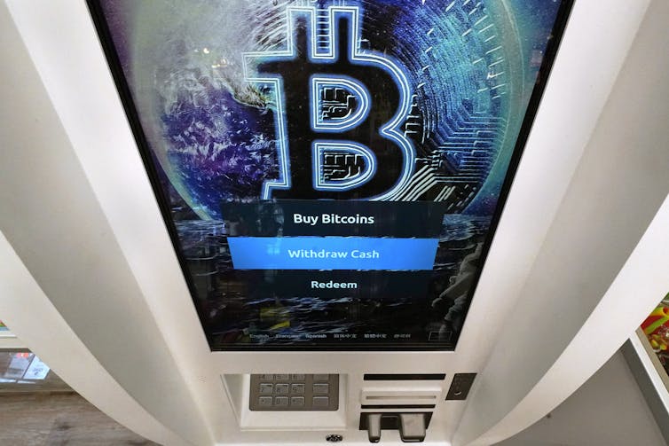 A bitcoin ATM with the bitcoin logo on its large screen and a small keypad at the bottom