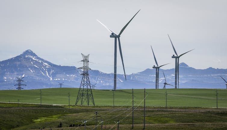 Power transmission lines and wind turbines as seen with mountains in the background