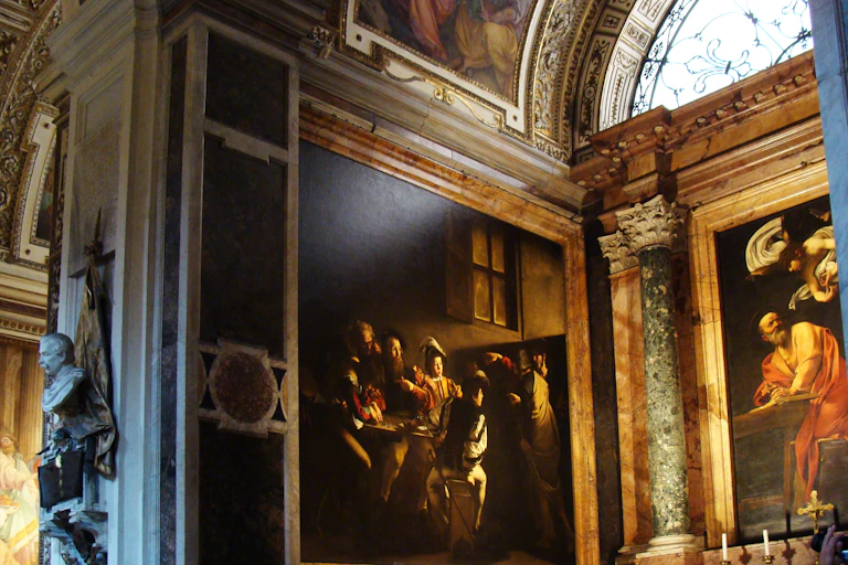 A large painting is on a wall of a dome-shaped hall, which has several frescoes adorning other walls.