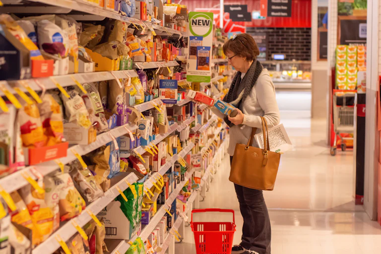 woman surveying two boxes of food at healthy food isle at Coles supermarket