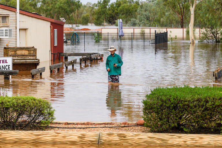 A man walking through floodwaters in Thargomindah, Queensland.