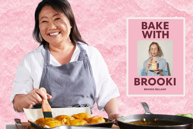 A smiling Asian woman cooking on a stove, wearing an apron