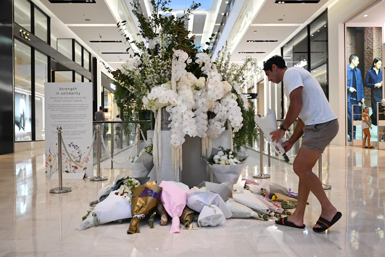 A man lays flowers at a memorial inside a shopping centre.