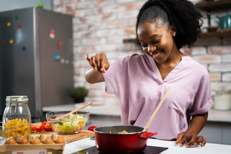 Young woman in kitchen cooking pasta.