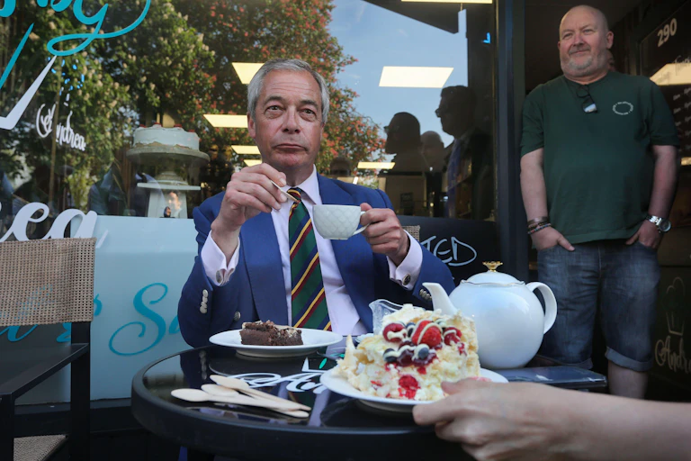 Nigel Farage eating tea and cake in a cafe.