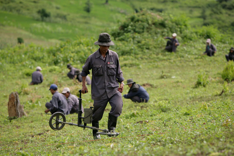 A team of mine clearance workers in a large field.