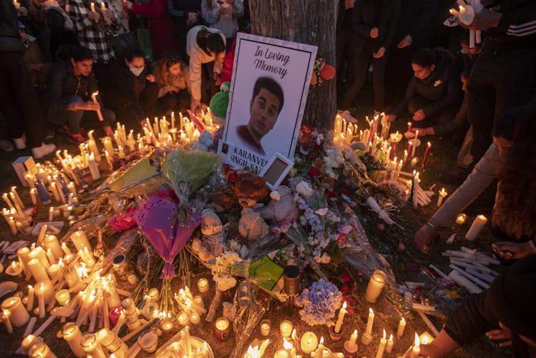 Cartel con adolescentes de cara rodeado de cientos de velas iluminadas.