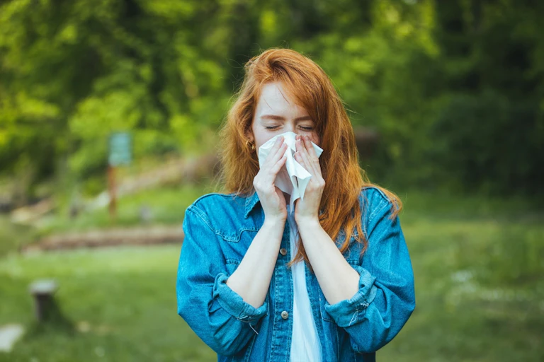 Woman blows her nose in the park