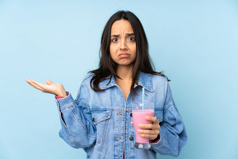 Woman looking confused and holding a strawberry milkshake