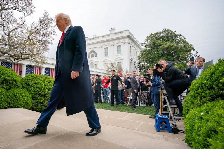 A man in a dark coat walking away from a small crowd of people, outdoors