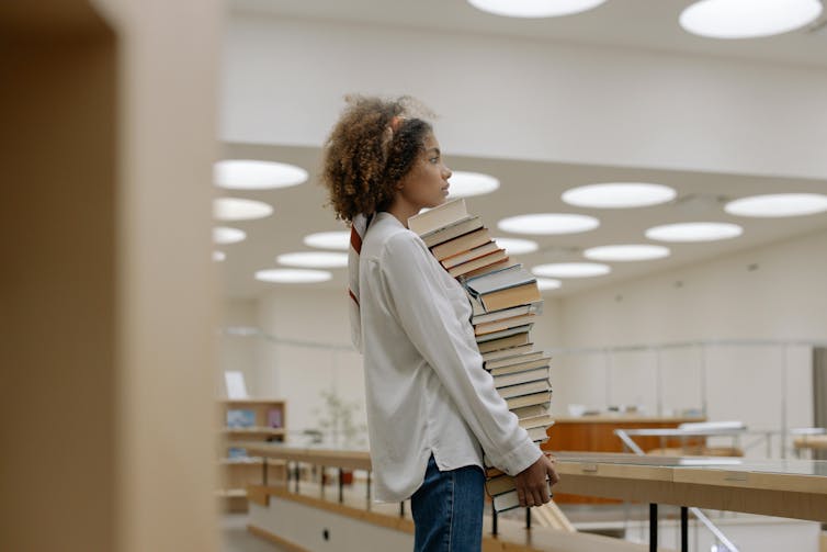 woman carrying pile of books