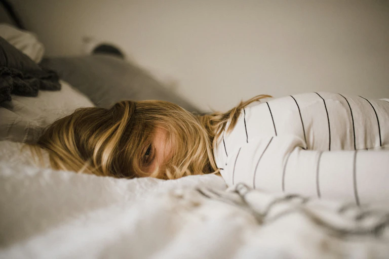 Young woman lays on bed