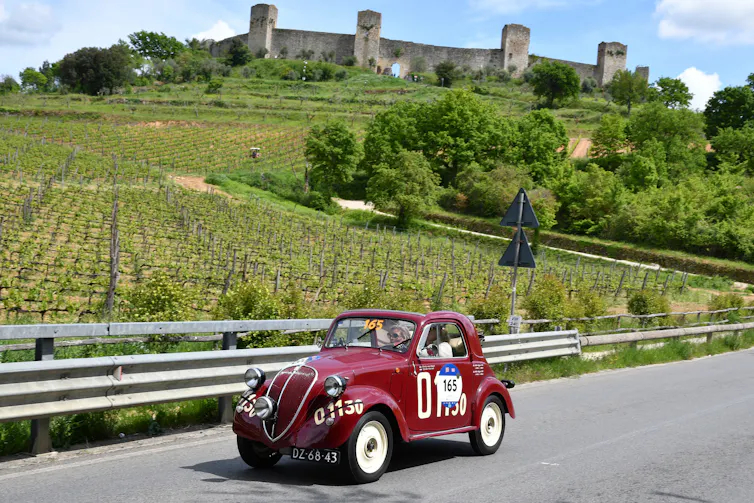 vintage fiat topolino driving through the italian countryside
