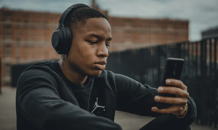 Boy looks at phone while listening to music