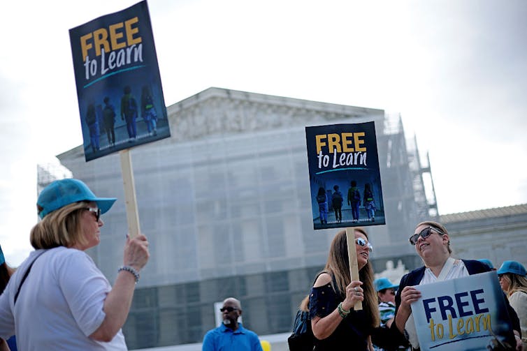 People hold signs as they gather outside the U.S. Supreme Court.