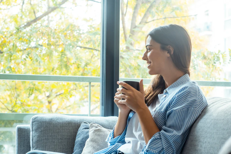 A young woman sitting on a couch drinking a cup of coffee