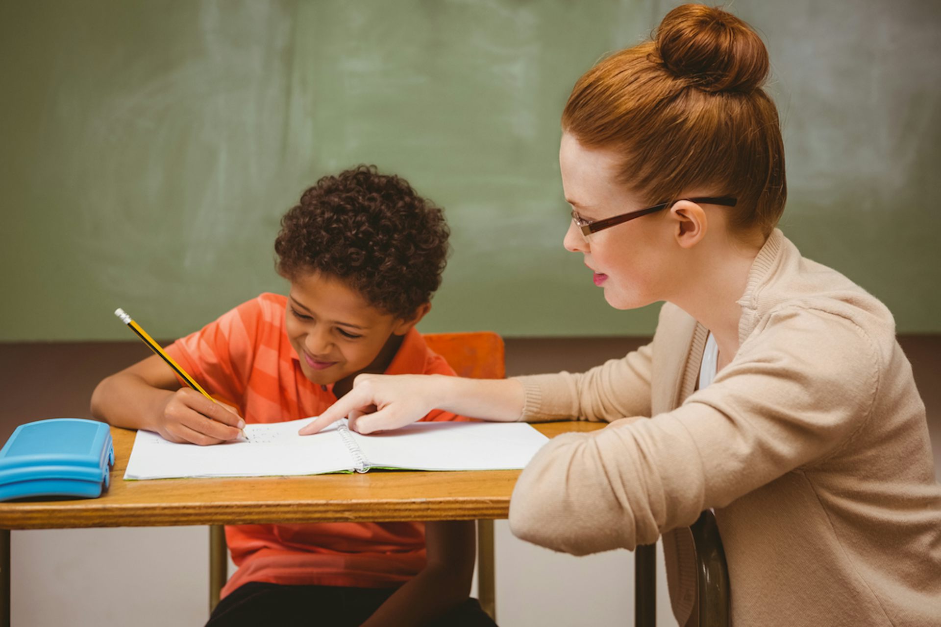 Une enseignante aide un élève à faire un exercice en classe