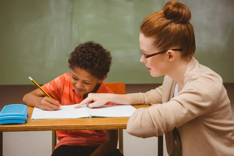 Une enseignante aide un élève à faire un exercice en classe