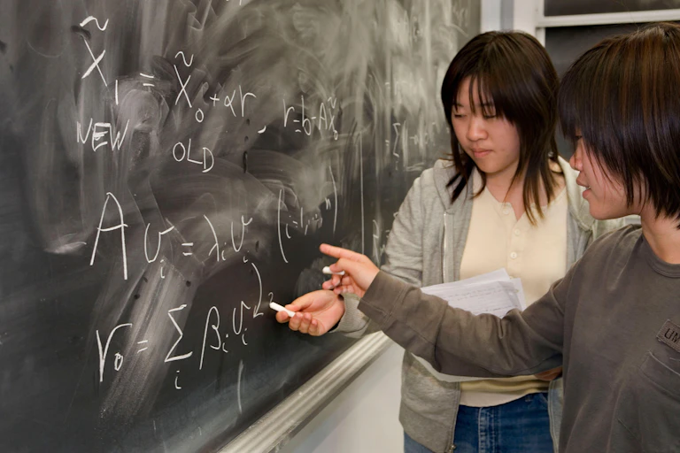 Two academics at a blackboard