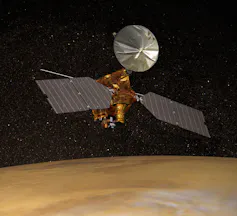 An illustration of a spacecraft with two large solar panels and a metal sheet in a circular shape orbiting around a dusty planet.