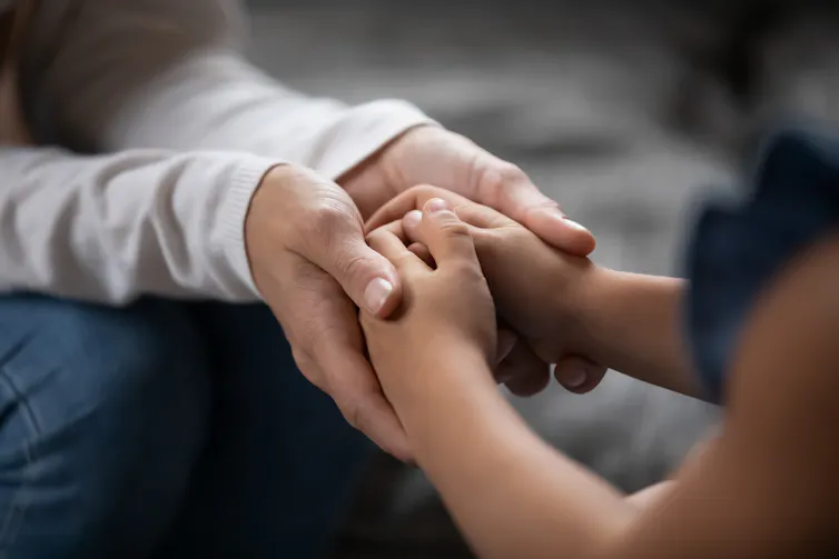 An adult holding a child's hands.
