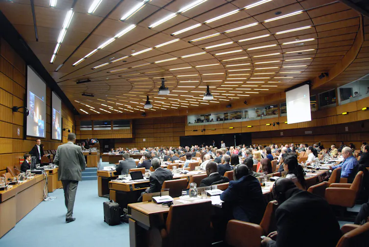 A semicircle-shaped room full of people sitting at tables.