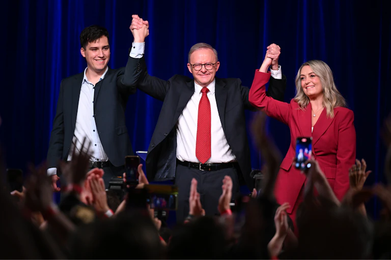 A man with a women and young man holding their hands in the air
