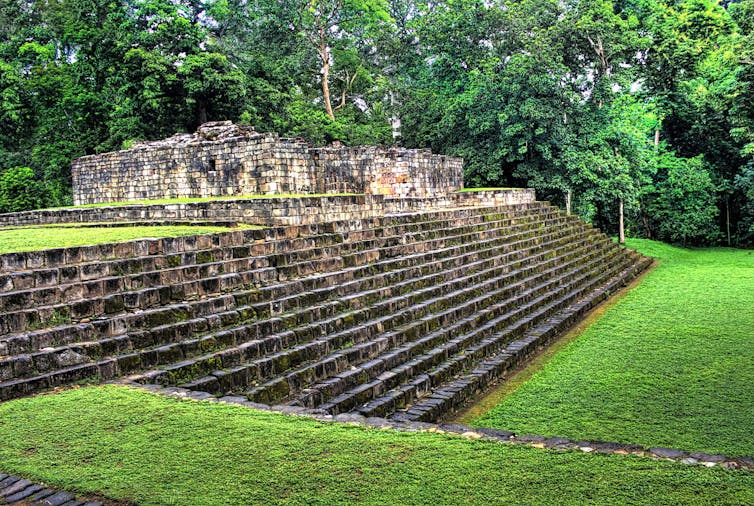 Stone stairs leading to ruins of buildings and flat areas covered in grass.