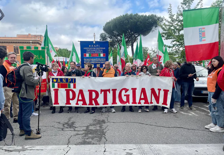 People marching behind a banner celebrating Italy's partisans.