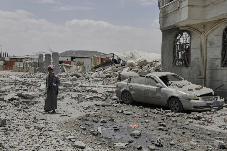 A man walks through a pile of rubble after a bombing.