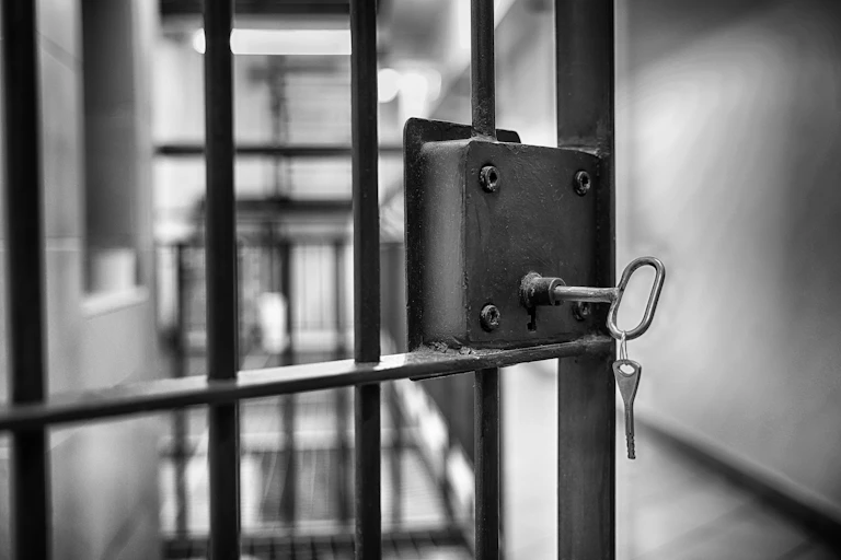Open interior prison gate with a key to a prison cell.