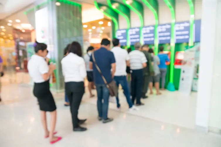 Blurred image of people line up to use an ATM.