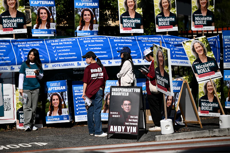 Volunteers for candidates are seen along with campaign corflutes and posters at the Killara High School polling booth on Federal Election Day, in the seat of Bradfield, in Sydney, Saturday, May 3, 2025.